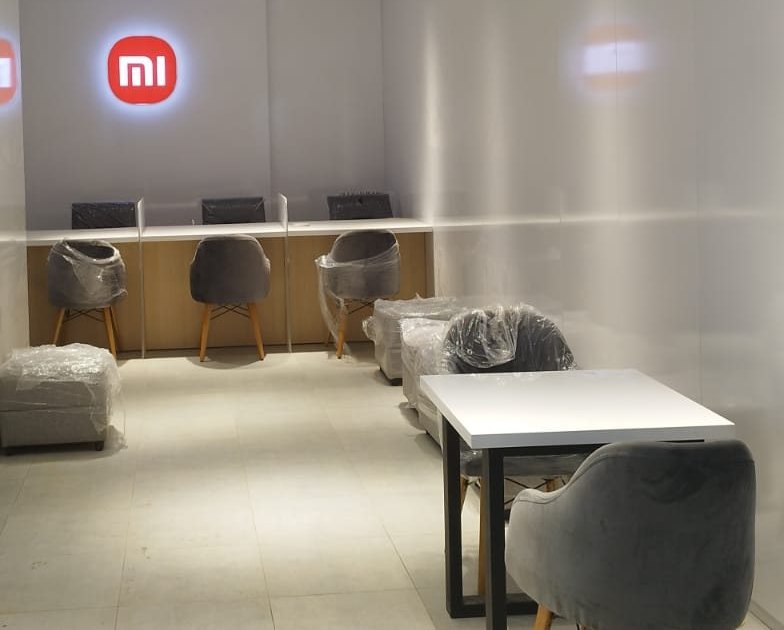 Xiaomi retail and customer-service space with backlit logo, product light panel and service counter with stools