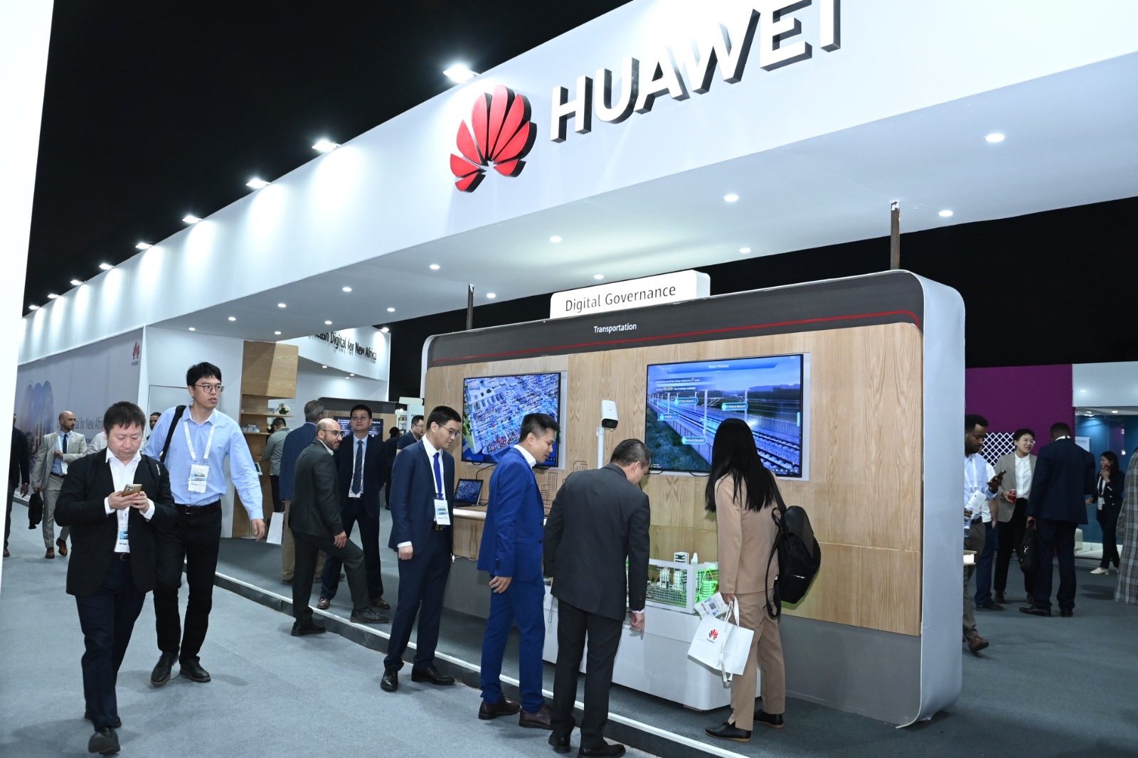 Huawei stand at GITEX Africa 2023 in Marrakech with white structure, illuminated Huawei header and wood-clad display wall