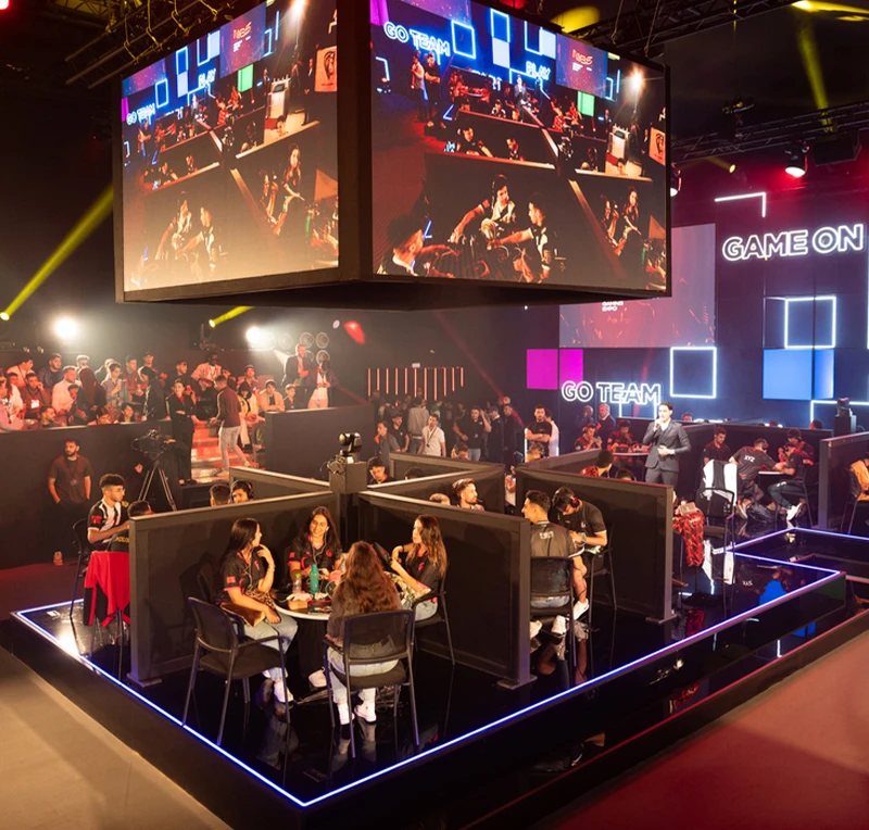 Esports tournament arena at Morocco Gaming Expo 2024 with neon-outlined stage, players and suspended screens