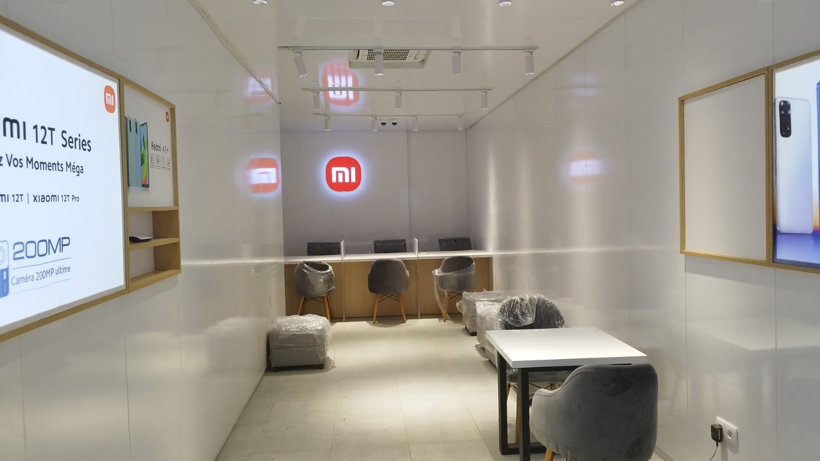 Xiaomi retail and customer-service space with backlit logo, product light panel and service counter with stools