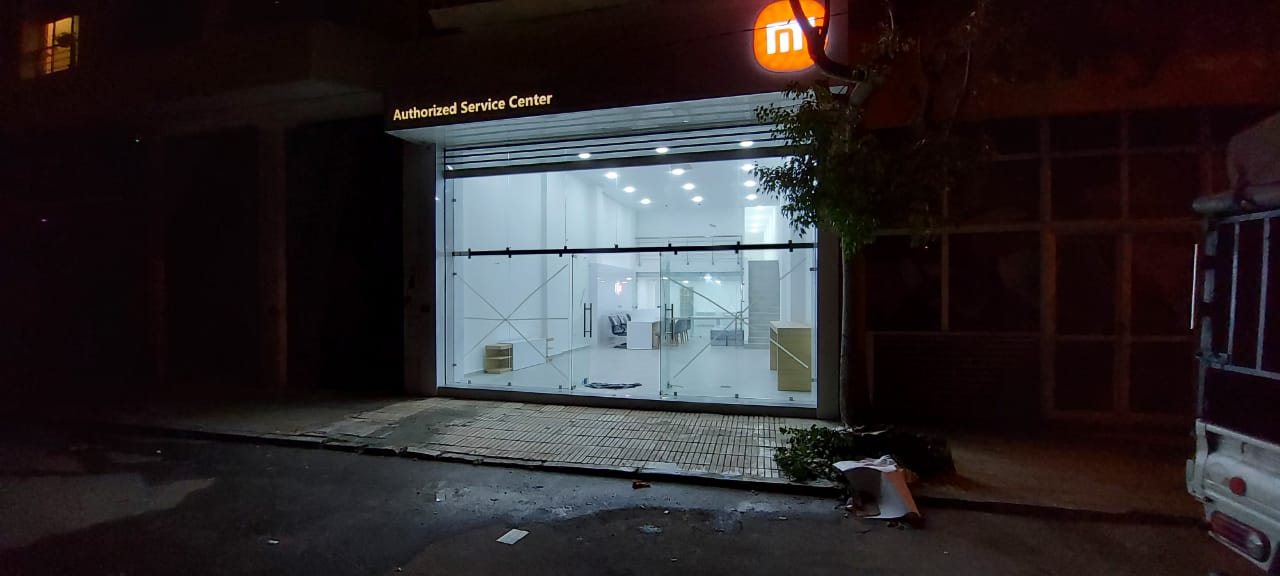 Xiaomi Authorized Service Center storefront lit at night, with the orange Mi sign